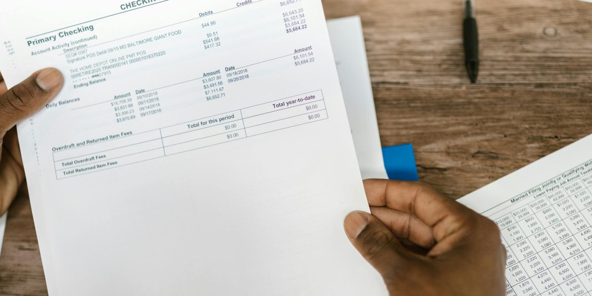A person reviewing financial documents, representing the importance of tracking income, expenses, and profitability.