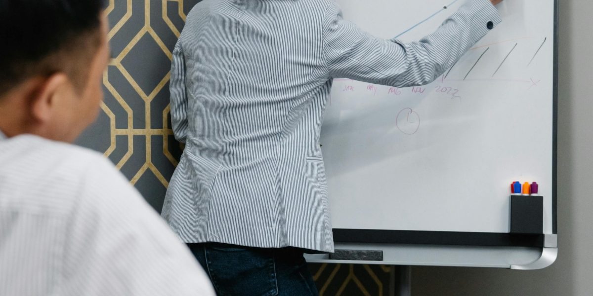 A person intently writing on a whiteboard, surrounded by sticky notes, symbolizing the process of brainstorming and strategic thinking.